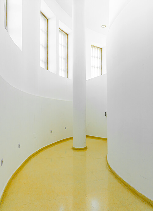 Pasillo blanco y limpio, con suelo amarillo y arquitectura en curva.