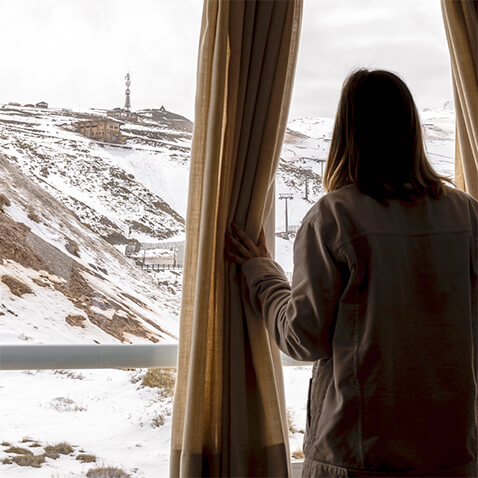 Joven mirando las pistas nevadas por la ventana del albergue Inturjoven Sierra Nevada
