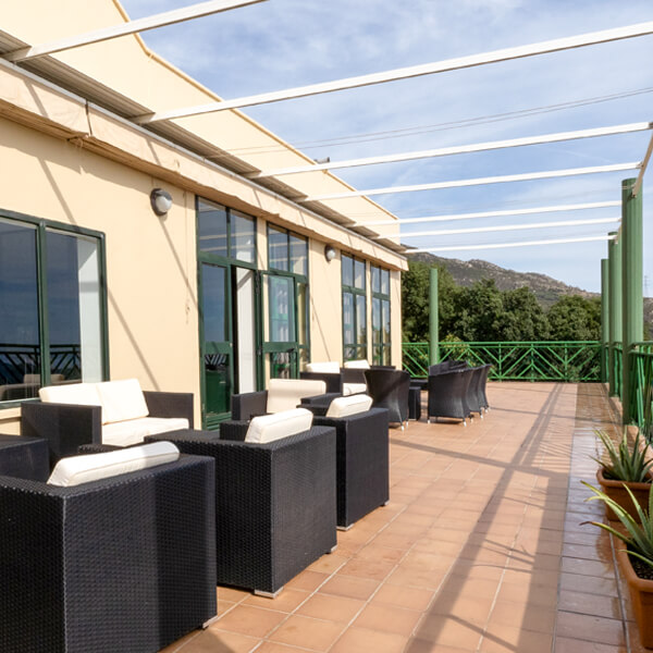 Terraza del Albergue con grandes ventanales, butacas y vistas a la sierra