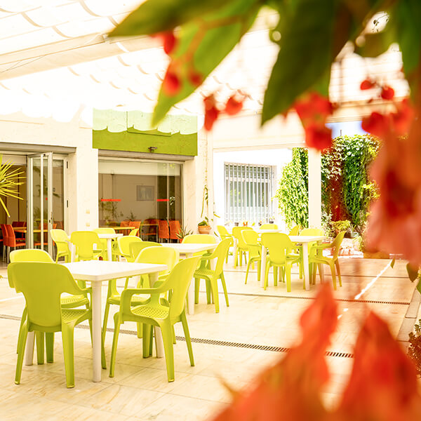 Vista a través de las buganvillas del patio interior, con mesas y sillas para descansar y pasar el rato