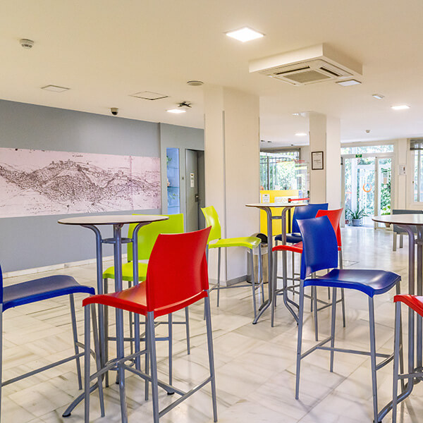 Zona de estar en la entrada del albergue, con mesas y sillas altas.