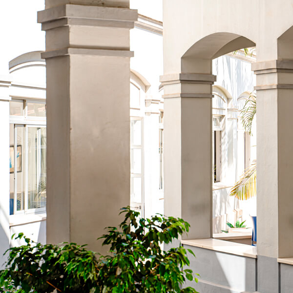 Galería interior con columnas, toldo y pequeños jardines