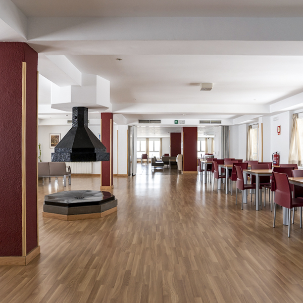 Salón de gran capacidad con chimenea central y vistas a las montañas