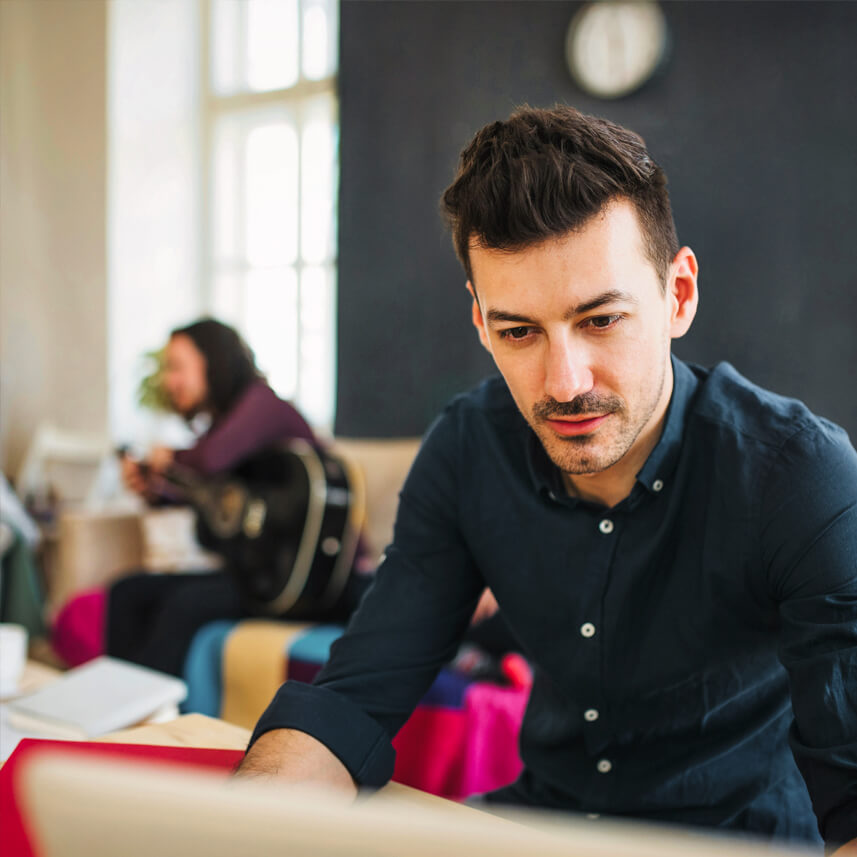 Coliving - Hombre joven trabajando en su portátil, en uno de los espacios comunes.