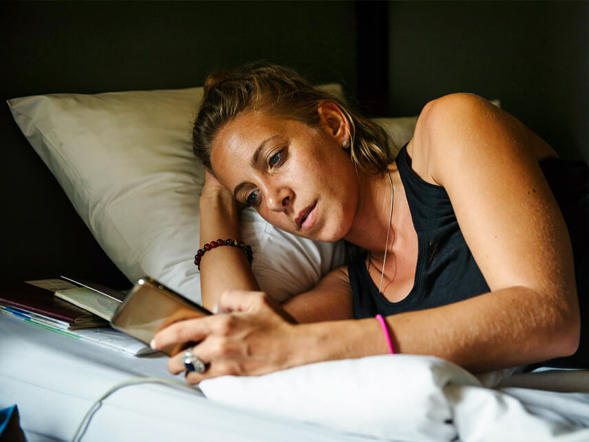 Coliving - Mujer echada en la cama de su habitación individual.